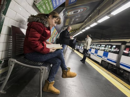 Una joven lee mientras espera el metro.