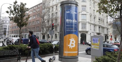 Un joven pasa junto a un panel de publicidad de bitcóin en Madrid.